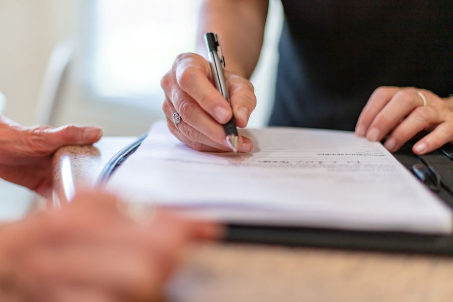 Eine Hand hält einen Kugelschreiber über einem Dokument.