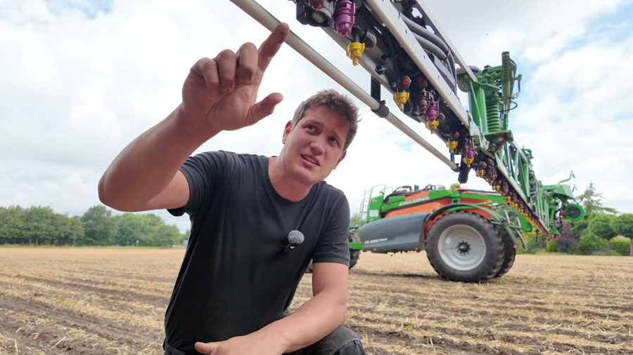 Landwirt kniet auf Acker erklärt und Spritztechnik.