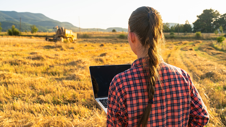 Landwirtin mit Laptop auf einem Feld.