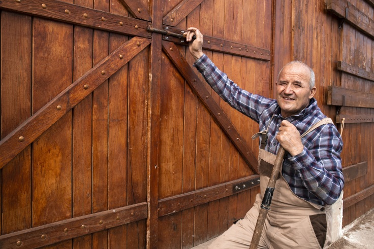 Älterer Bauer schließt Scheunentor und damit symbolisch seinen Bauernhof