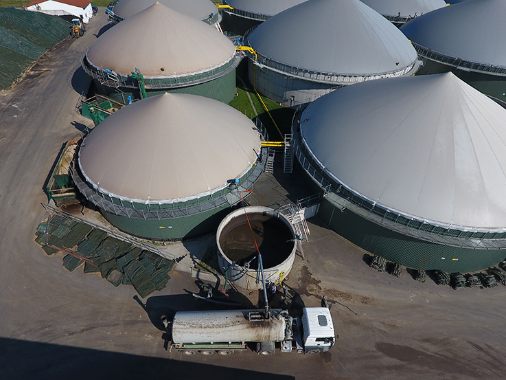 Luftaufnahme einer Biogasanlage. Ein LKW mit Güllefass wird mit Gärrest befüllt.