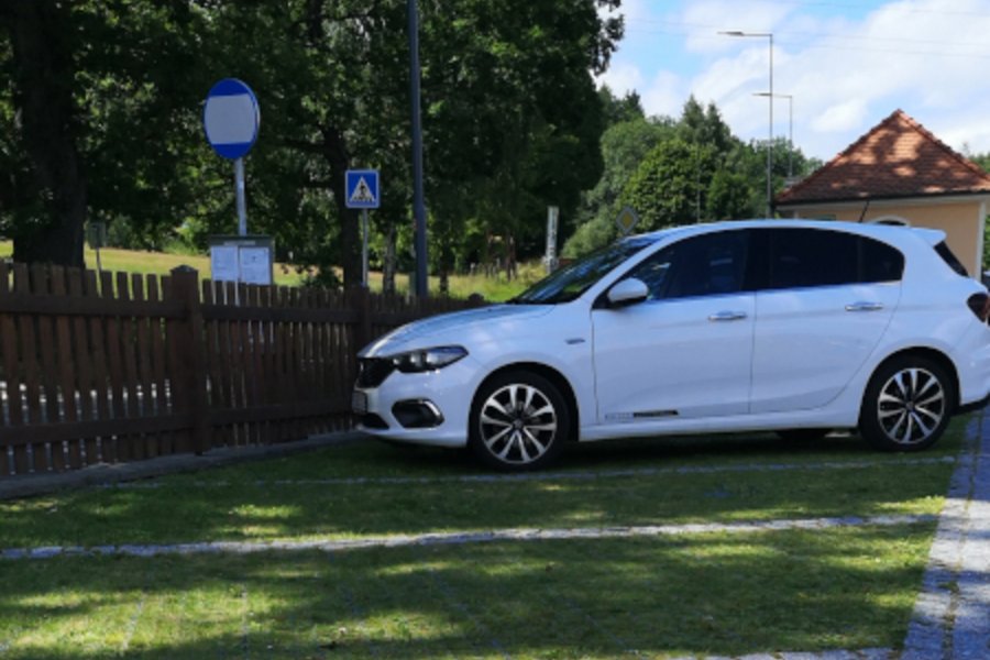 Ein Auto steht auf einer Parkfläche aus Rasengittersteinen. In den Steinen wächst Gras.
