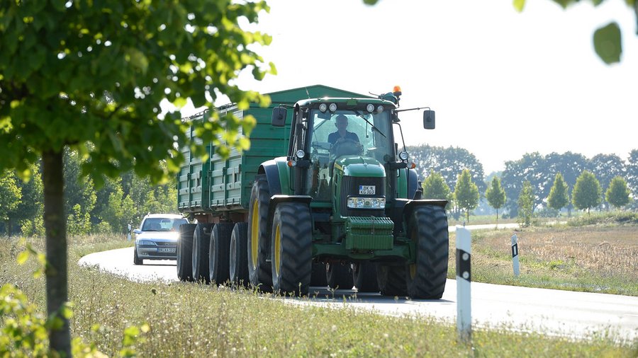 Traktor mit zwei Anhängern auf einer Landstraße