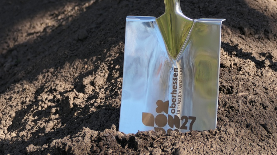 Ein Spaten mit Logo der Landesgartenschau steckt in der Erde.
