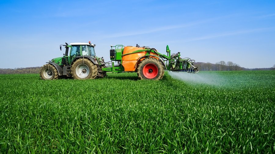 Pflanzenschutz-Applikationen werden mit einem Traktor auf ein Feld aufgebracht.