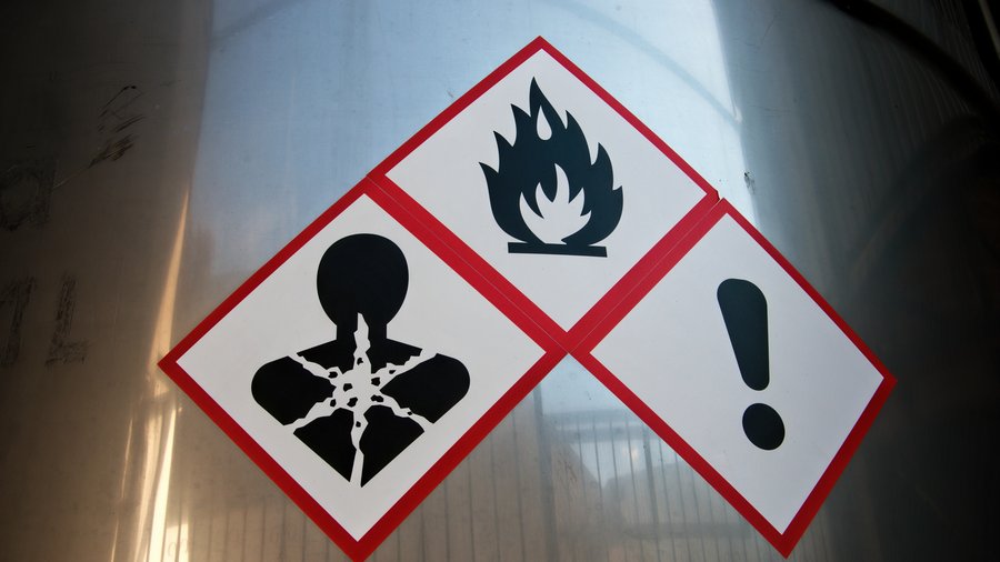 Hazard warning symbols on a stainless steel vat in a factory