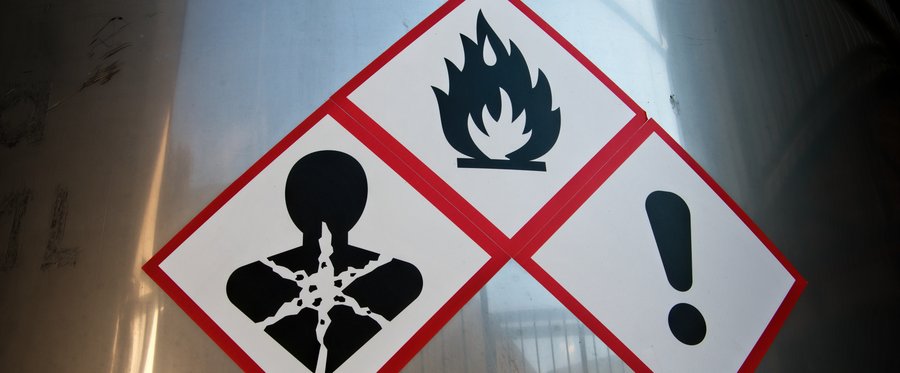 Hazard warning symbols on a stainless steel vat in a factory