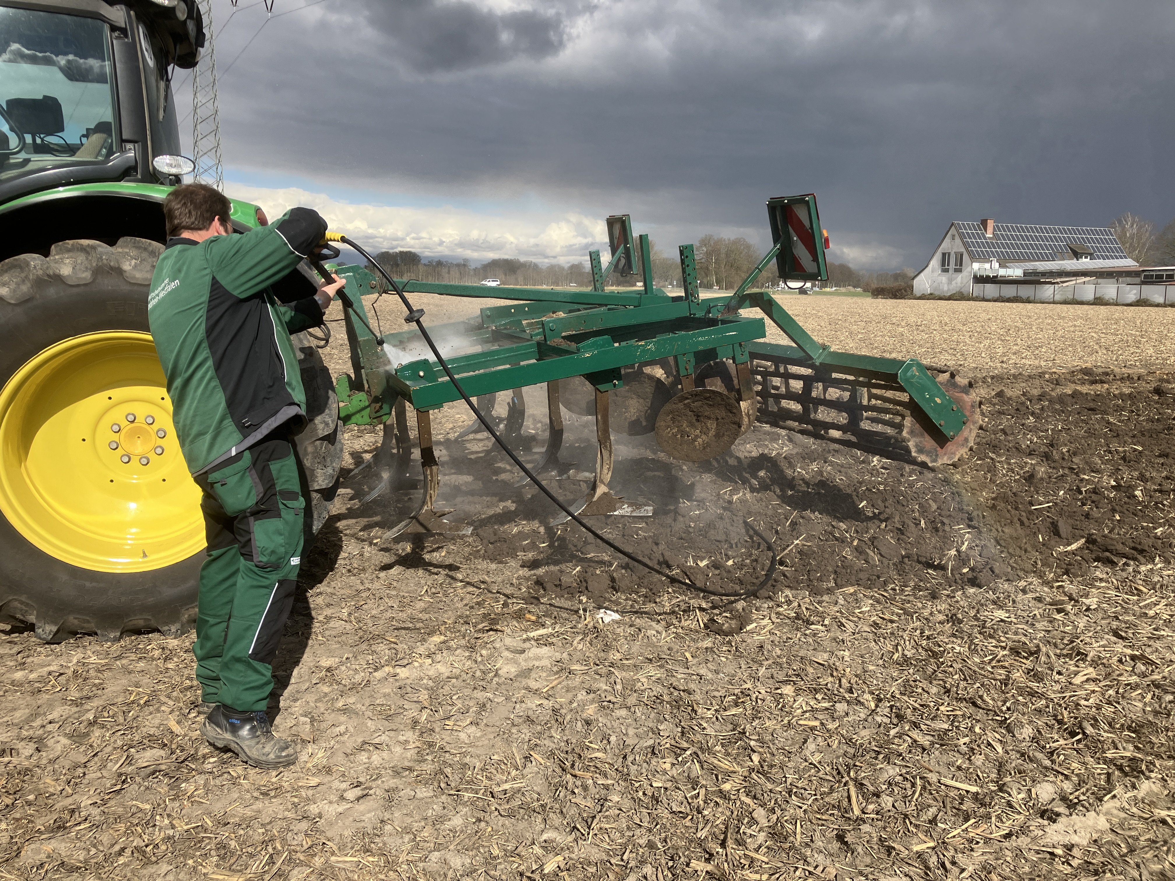 Eine landwirtschaftliche Maschine wird mit dem Hochdruckreiniger von Erdresten befreit.