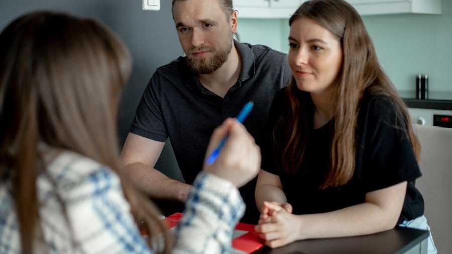 Drei Personen sitzen im Gespräch zusammen an einem Tisch.