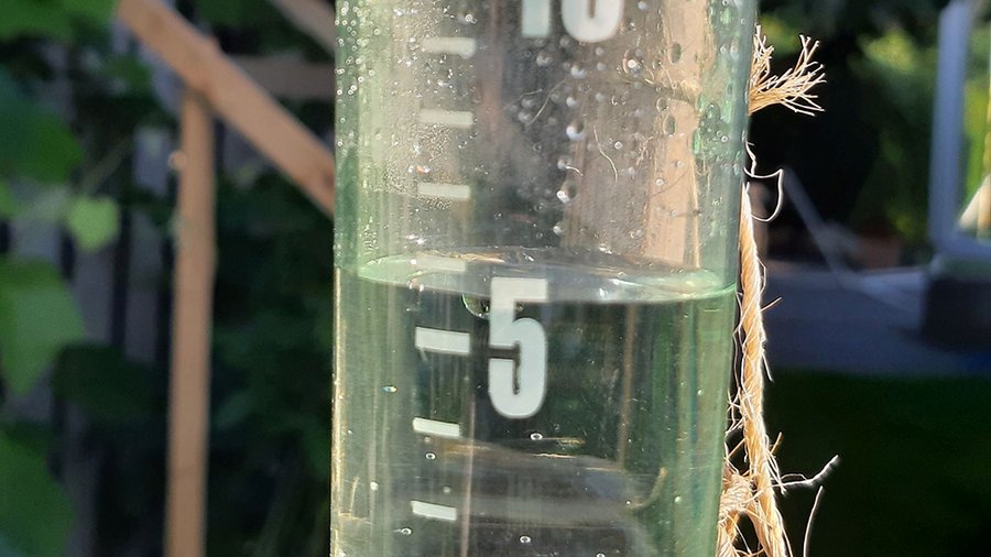 Regenmesser aus Plexiglas mit Skalierung und einen niedrigen Wasserstand von etwas mehr als 5 mm Niederschlag.