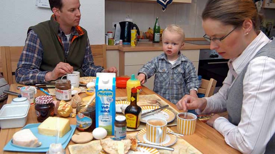 Vater, Mutter und Kind beim gemeinsamen Frühstück.