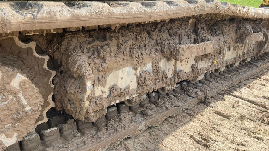 Mit Erde bedecktes Fahrwerk einer landwirtschaftlichen Maschine.