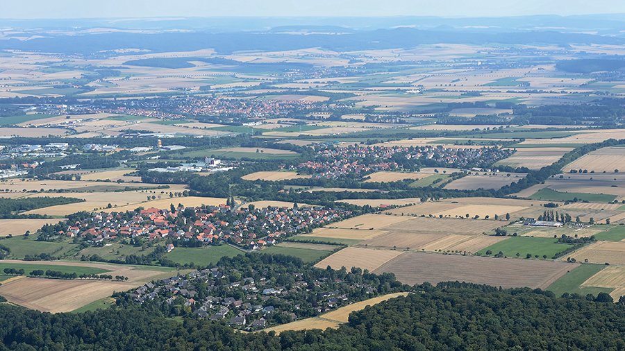 Eine Landschaft mit ländlichen Strukturen von oben, Dörfer liegen inmitten einer großen Feldmark.