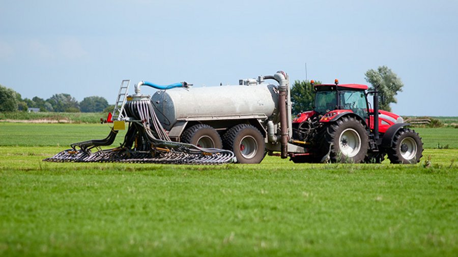 Schlepper mit Güllefass verteilt Wirtschaftsdünger.