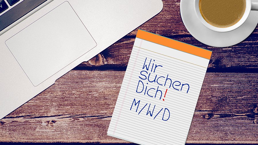 Blick von oben auf Tisch aus dunklen Holzbohlen. Darauf liegt ein Notizblock mit Aufschrift Wir suchen dich m/w/d. Ein Laptop und eine Kaffeetasse sind im Anschnitt zu sehen. Bild: studio v-zwoelf/stock.adobe.com 