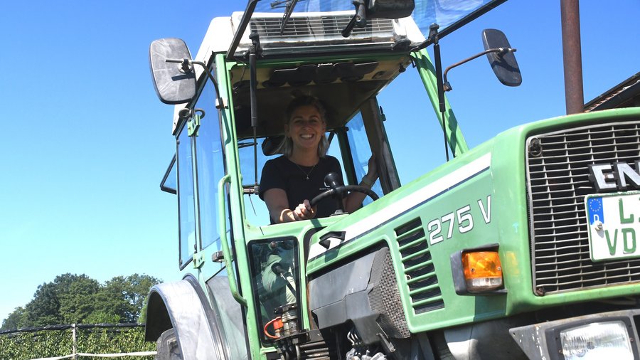 Lena Nüberlin sitzt auf einem Traktor und lacht in die Kamera.