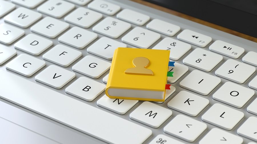 Tastatur, auf der ein kleines gelbes Adressbuch liegt.