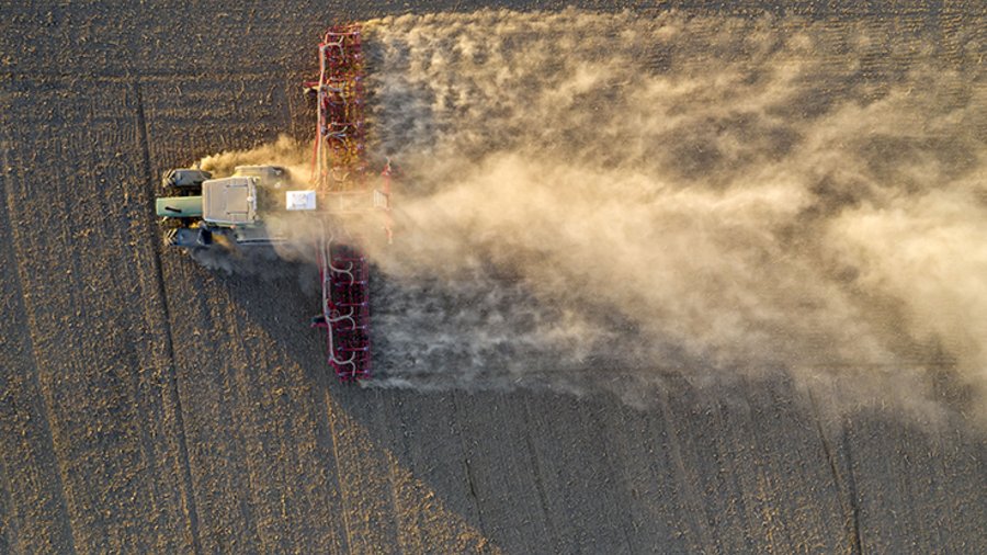 Luftbild von einem Traktor bei der Aussaat. Aufgrund der extremen Trockenheit kommt es zu starker Staubbildung.