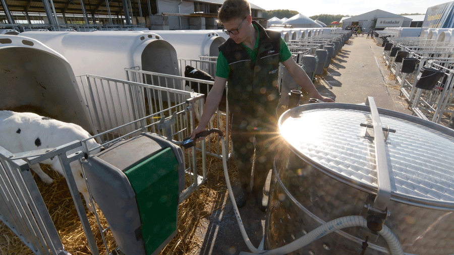 Ein Mann bringt Milch mit einem Milchtaxi zu den Kälbern. Klick führt zu Großansicht im neuen Fenster.