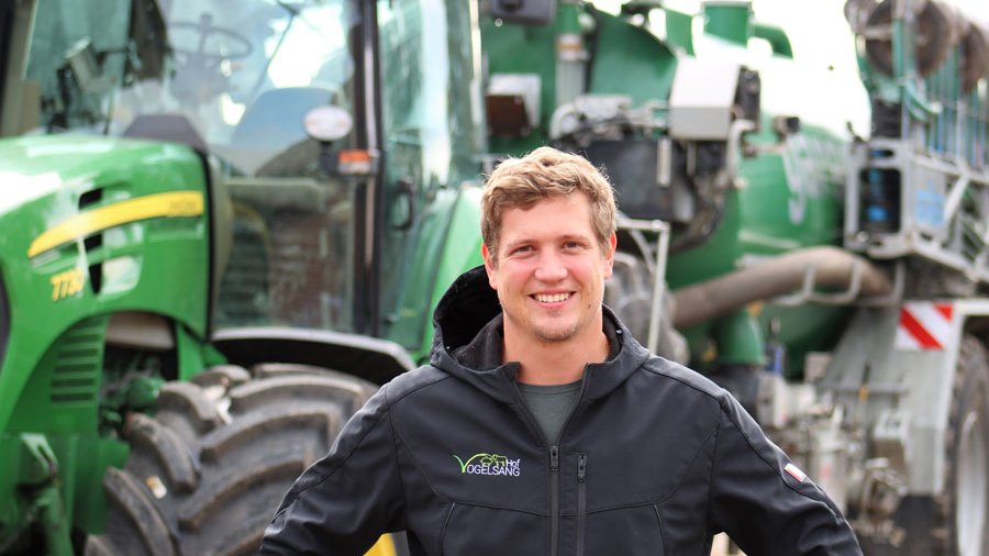 Landwirt steht vor einem Traktor.