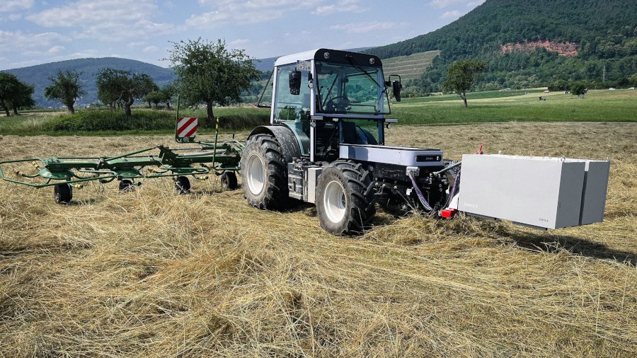 Der Prototyp des elektisch betriebenen Traktors steht auf einer Wiese.