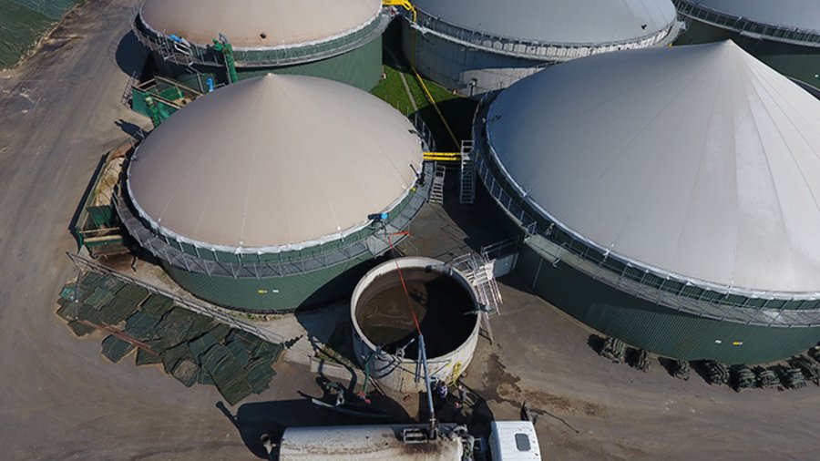 Luftaufnahme einer Biogasanlage. Ein LKW mit Güllefass wird mit Gärrest befüllt.