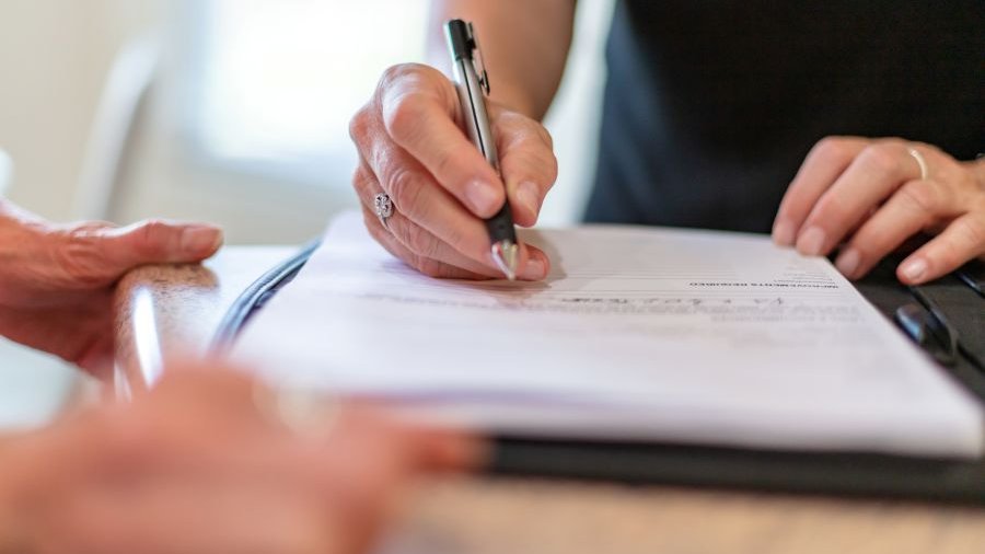 Eine Hand hält einen Kugelschreiber über einem Dokument.